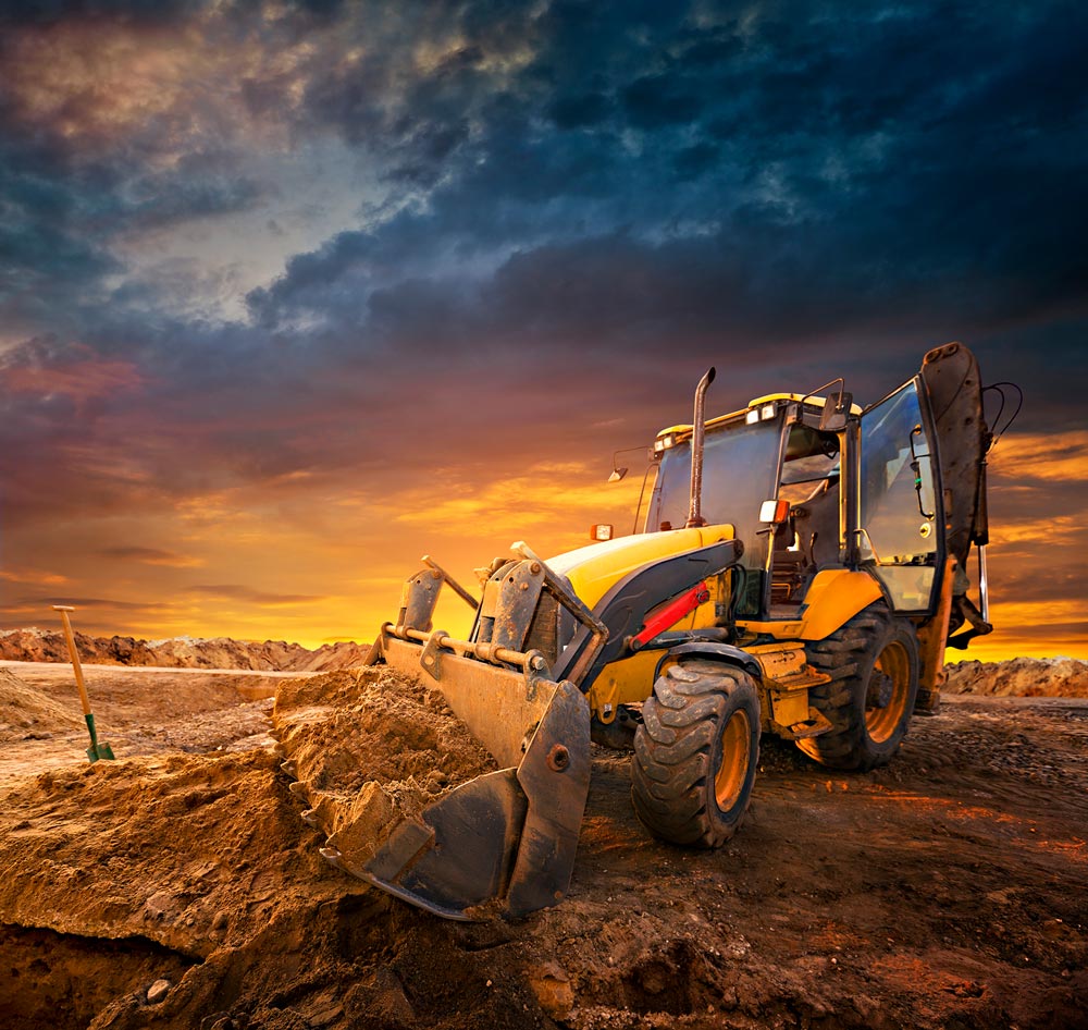 Overholt Grading - commercial and residential grading excavating paving - bobcat on cleared land agasint a sky at dusk