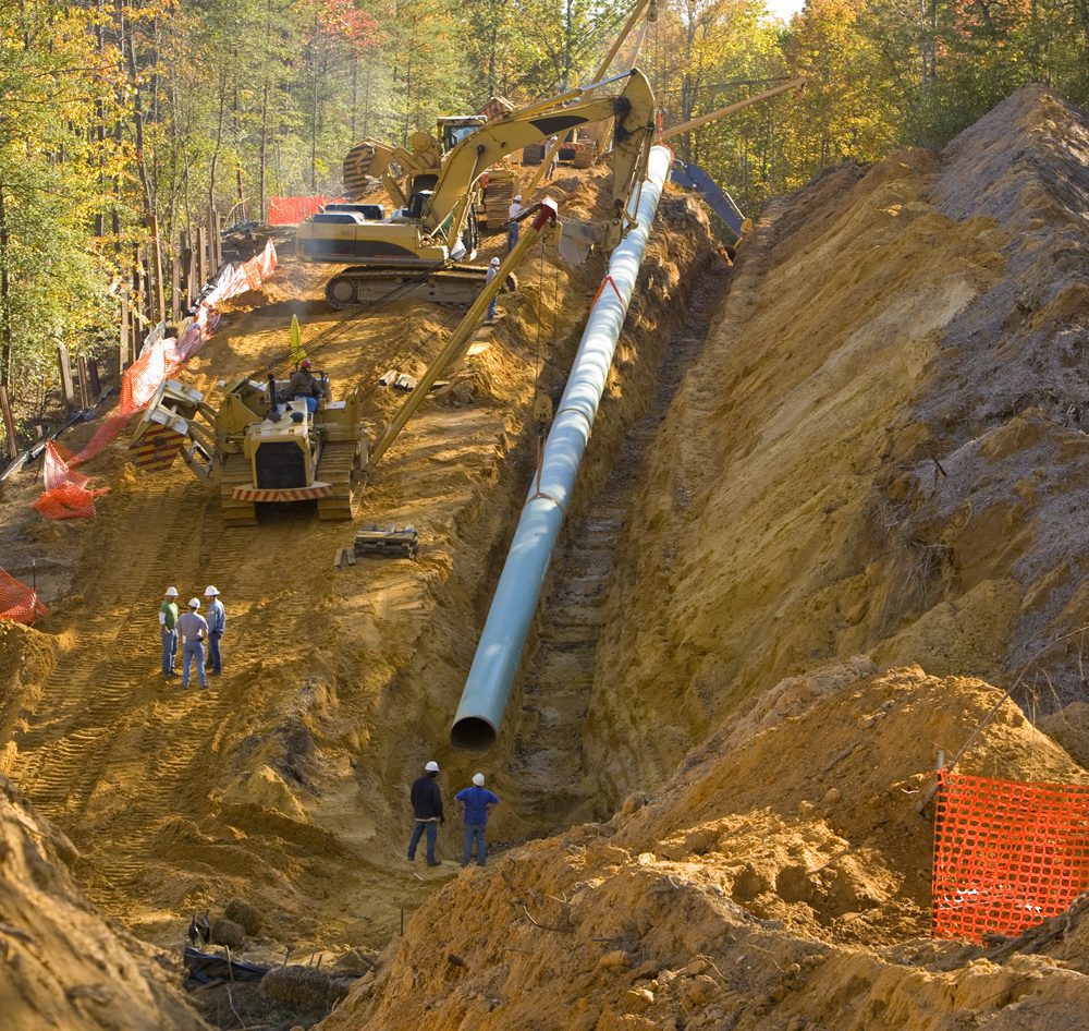 Overholt Grading - crew and equipment clearing trees and making a ditch for a pipe on a hill